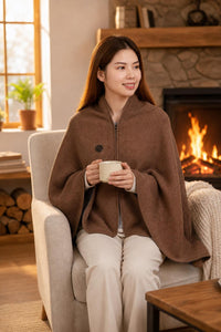 Mujer usando el Poncho Térmico Eléctrico MyHeron color café junto a la chimenea